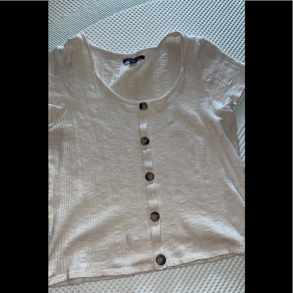 Off white t-shirt. Kind of fit likes a crop top. Buttons are just decoration.